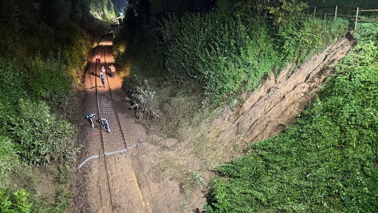 27.07.2025, Baden-Württemberg, Riedlingen: Einsatzkräfte arbeiten an den Gleisen nahe eines Erdrutsches. 