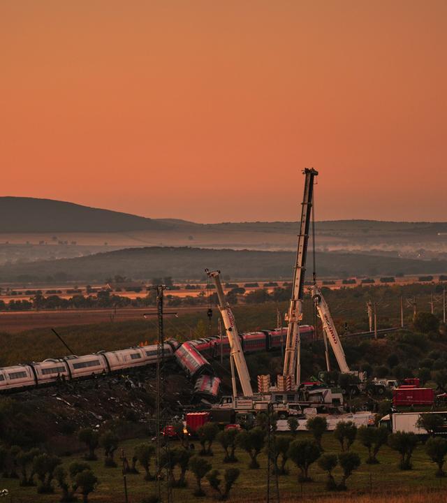  Kräne heben die zerstörten Zugwaggons an, während Rettungskräfte nach der Kollision zweier Züge nach Opfern suchen.