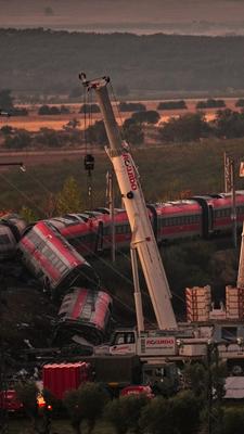 Kräne heben die zerstörten Zugwaggons an, während Rettungskräfte nach der Kollision zweier Züge nach Opfern suchen.