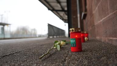 Kerzen und Blumen vor einem Bahnhofsgebäude