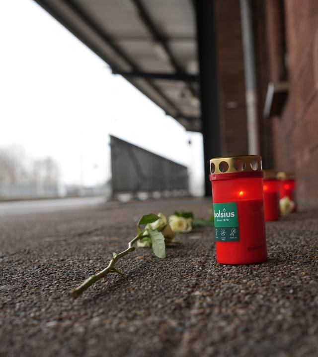 Kerzen und Blumen vor einem Bahnhofsgebäude