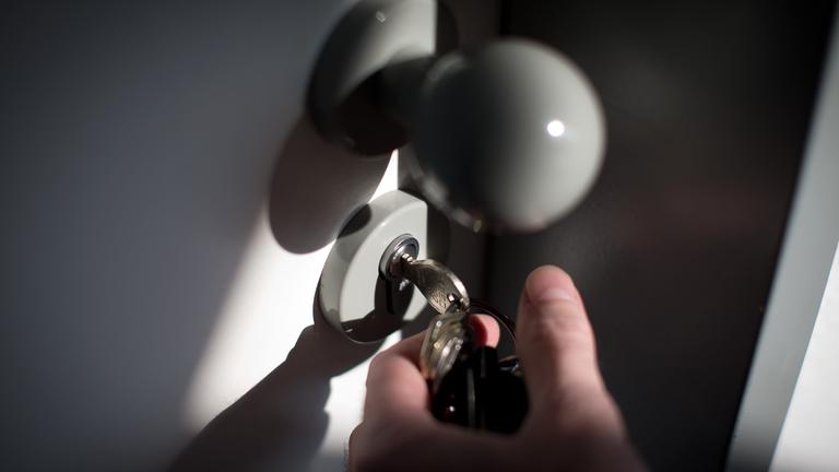 In einer Tür, die geöffnet wird steckt ein Schlüssel.