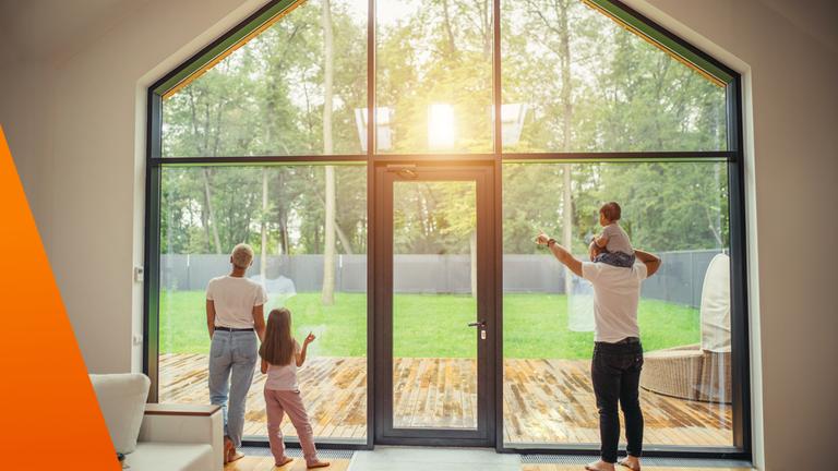 Familie schaut aus gro?em Fenster aus Wohnung in den Garten