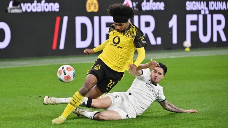 Mönchengladbachs Kevin Diks grätscht im Zweikampf Dortmunds Karim Adeyemi samt Ball um.