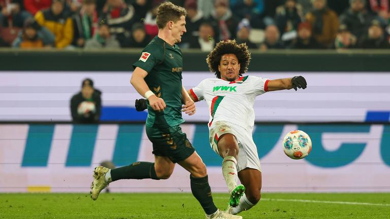 Augsburgs Han-Noah Massengo grätscht im Zweikampf mit Bremens Jens Stage in Richtung Ball um seinen Gegenspieler zu stoppen