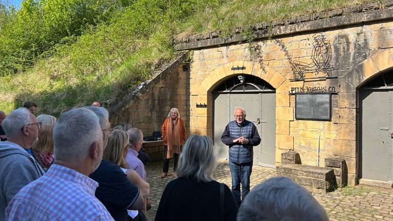 Eine Gruppe hört einem Redner bei einer Führung durch die Gedenkstätte in der Festung von Queuleu.