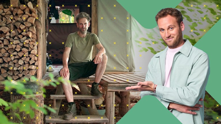 Dr. Leon Windscheid steht lächelnd im Vordergrund und zeigt zur Seite. Im Hintergrund sitzt Marc Freukes vor einer Holzhütte im Wald. Neben ihm liegt ein großer Stapel Brennholz.